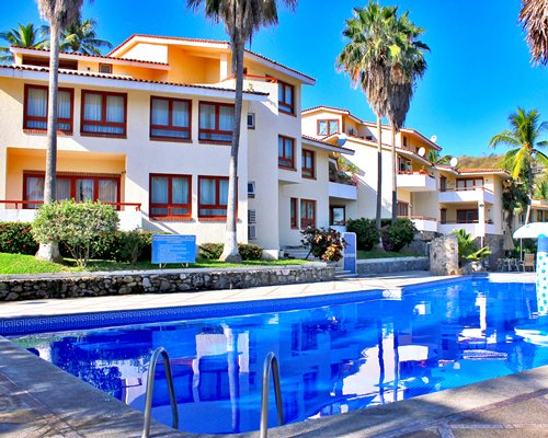 An outdoor swimming pool alongside multi story resort units.
