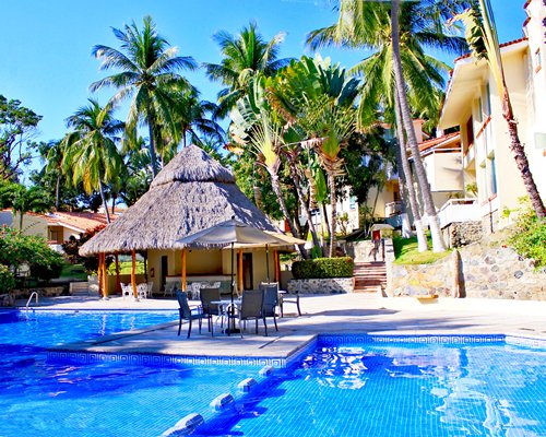 An outdoor swimming pool with patio furniture alongside multi story resort units.