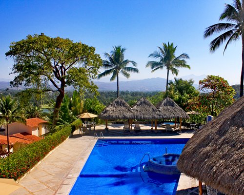 Outdoor swimming pool with poolside bar chaise lounge chairs and thatched sunshades.