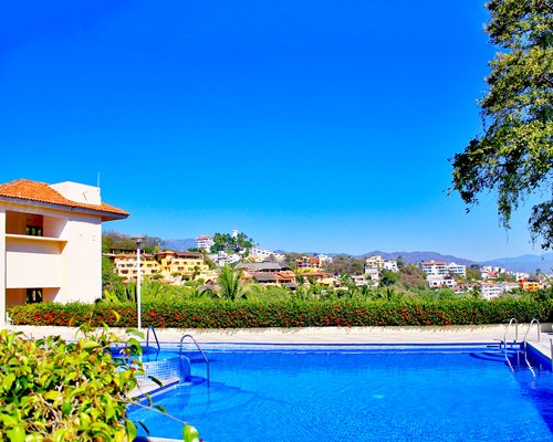 A scenic outdoor swimming pool with hot tub alongside multiple resort units.