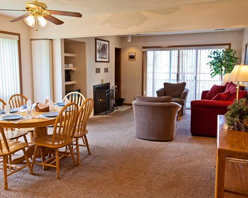 A well furnished living and dining area with television fire at the fireplace and an outside view.