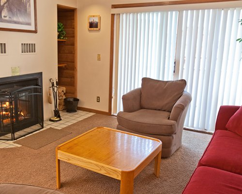 A well furnished living room with a fire in the fireplace and an outside view.