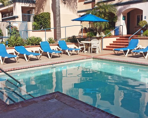 An outdoor swimming pool with chaise lounge chairs and patio furniture alongside resort units.