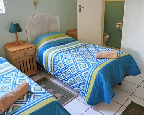 A bedroom room with twin beds and an enclosed bathroom.