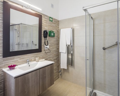 A bathroom with a stand up shower sink and mirror.