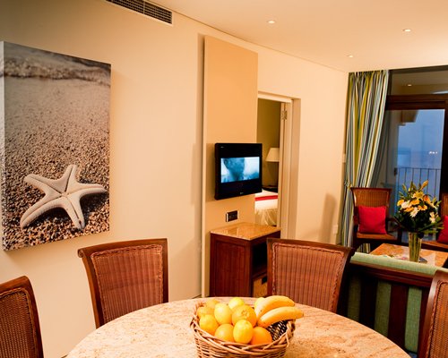 A well furnished dining area alongside a television.