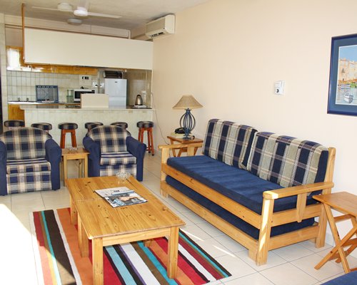 A well furnished living room with an open plan kitchen and breakfast bar.