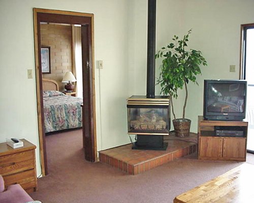 A well furnished living room with a television fireplace and view of a bedroom.