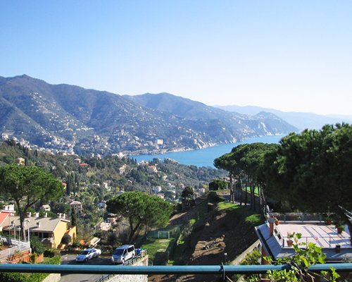 Exterior view of Portofino Est Residence surrounded by wooded area alongside ocean from balcony.