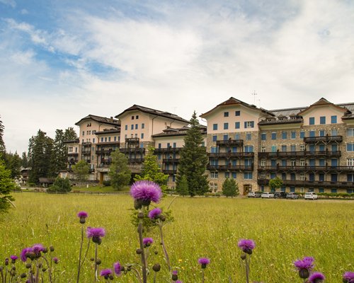 Exterior view of Residence Grand Hotel Carezza surrounded by wooded area during winter.