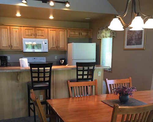 An open plan kitchen with breakfast bar and wooden dining area.