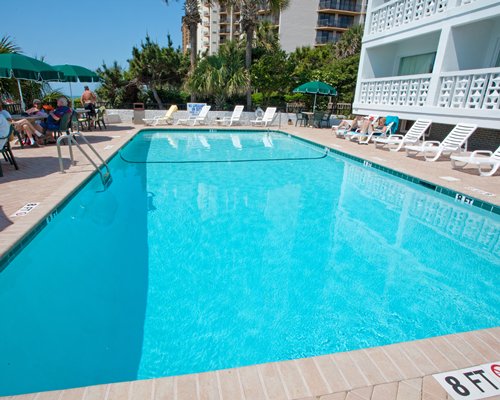 An outdoor swimming pool with chaise lounge chairs alongside the resort units.
