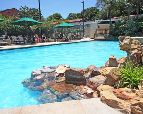 Outdoor grotto pool with chaise lounge chairs and sunshades.