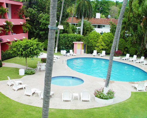 Scenic outdoor swimming pool with chaise lounge chairs alongside resort units.