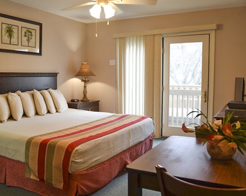 A well furnished bedroom with a queen bed dining area and outdoor view.