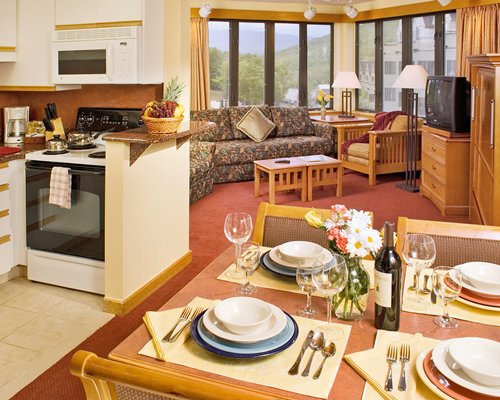 A well furnished living room with a television dining area and open plan kitchen.