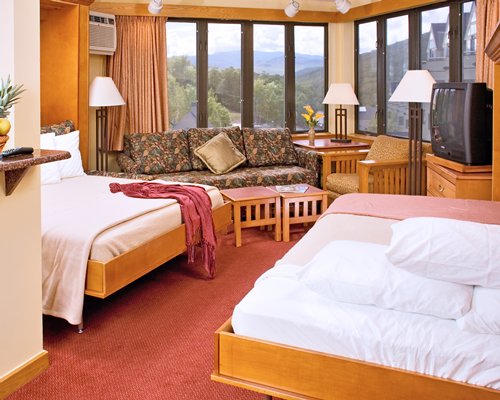 A well furnished living room with television and two king beds.