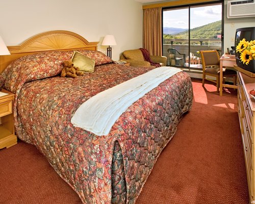 A well furnished bedroom with king bed television and balcony.