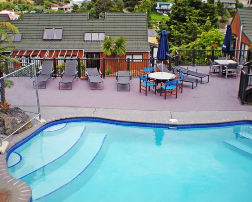 An outdoor swimming pool with chaise lounge chairs alongside the resort units.