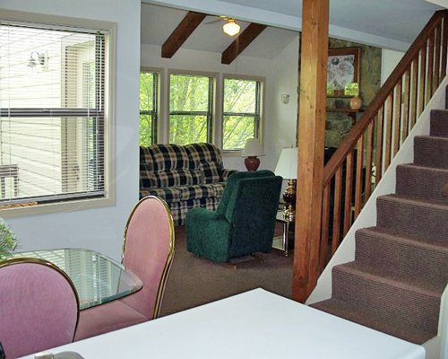 A well furnished dining room with a stairway alongside a living room.