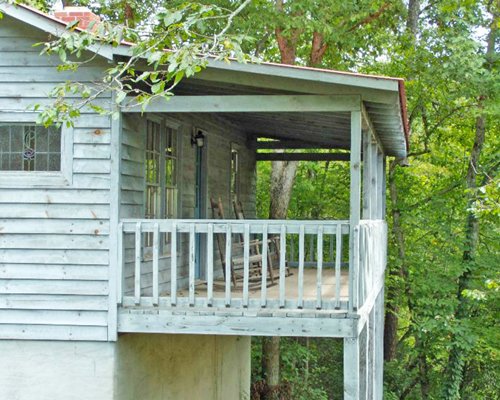 Exterior view of a unit with balcony surrounded by wooded area.