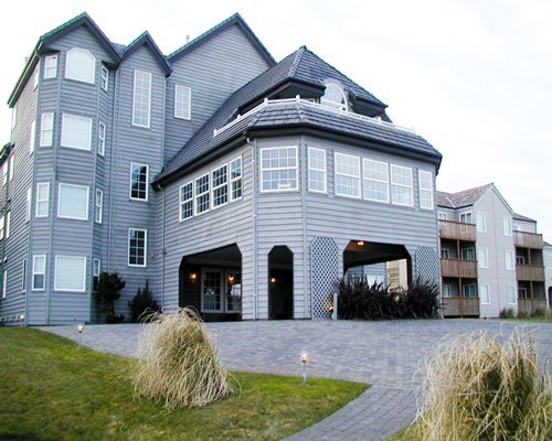 An exterior view of multi story resort units alongside a well maintained lawn.
