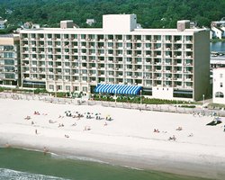 An aerial view of multi story resort alongside the beach.