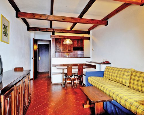 A well furnished living room with a television alongside kitchen with a breakfast bar.
