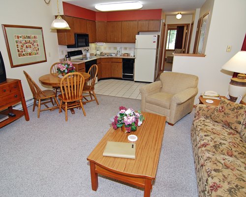 A well furnished living room with an open plan kitchen dining area and television.