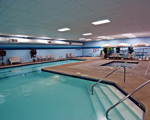 An indoor swimming pool and hot tub with patio furniture.