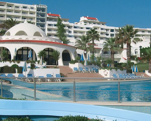 A scenic view of a large outdoor swimming pool alongside the resort.