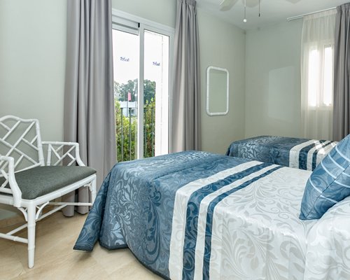 A well furnished bedroom with two twin beds and balcony.