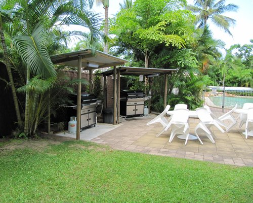 Outdoor swimming pool with patio furniture and two barbecue grills.