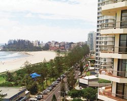 Scenic exterior view of Beach House Seaside Resort with parking lot alongside the beach.