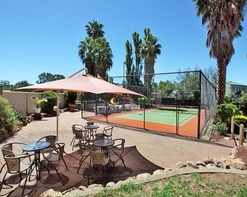 Outdoor dining with sunshades and pathway to tennis court.