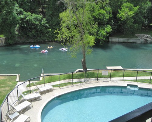 An aerial view of an outdoor swimming pool alongside the waterfront.