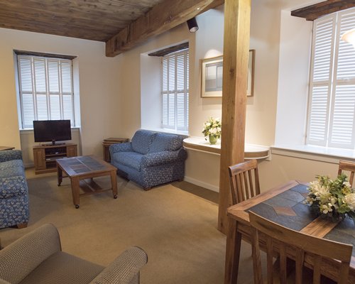 A well furnished living room with television and dining table.