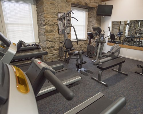 A well equipped indoor fitness center with television.