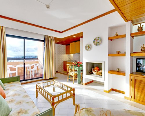 A well furnished living room with a television dining area balcony and ocean view.