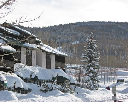 Snow covered exterior view of Goldenwoods Condominiums At Powderhorn Resort alongside mountains.