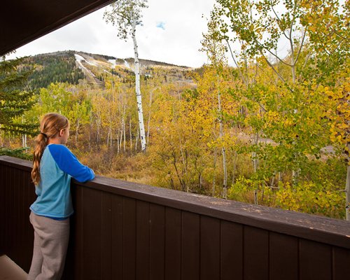 A girl standing on the balcony facing outside view.