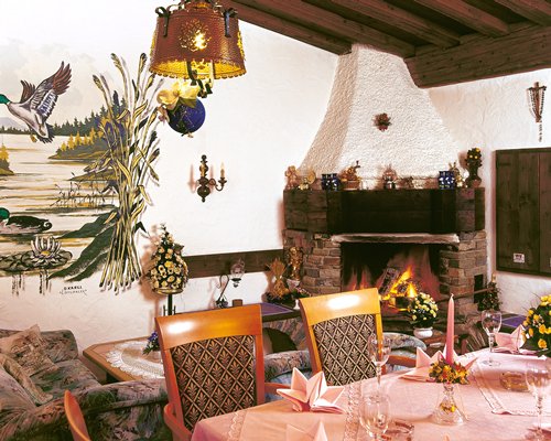 A well furnished living room with dining area and fire in the fireplace.