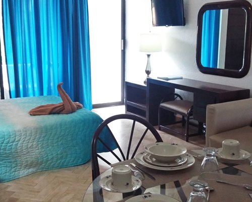 A well furnished bedroom with television and dining area.
