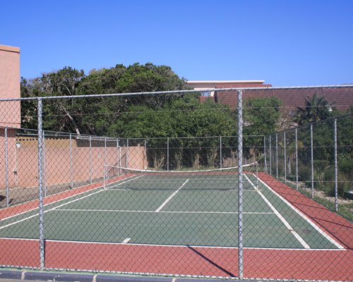 Outdoor recreation area with tennis court surrounded by wooded area.