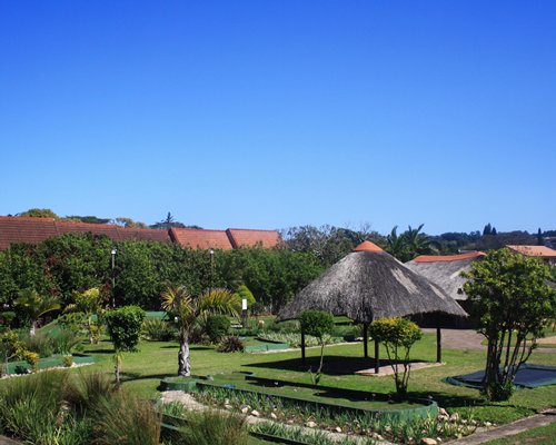 An outdoor picnic area with thatched sunshades and landscaping.