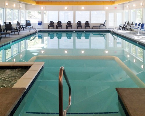 A LARGE INDOOR SWIMMING POOL WITH PATIO FURNITURE.