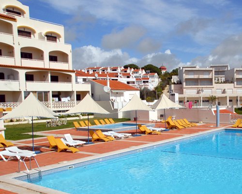 Exterior view of an outdoor swimming pool with chaise lounge chairs alongside Albufeira Jardim 2 resort.