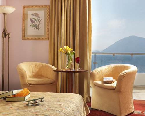 A well furnished bedroom with two sofas and a balcony.