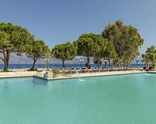 A large outdoor swimming pool with chaise lounge chairs alongside the waterfront.