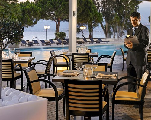 Outdoor swimming pool and restaurant with chaise lounge chairs and landscaping.